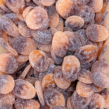 A close-up pile of dried orange-brown fruit slices, likely apricots or dried apricots, coated with sugar and showing a textured, translucent surface.